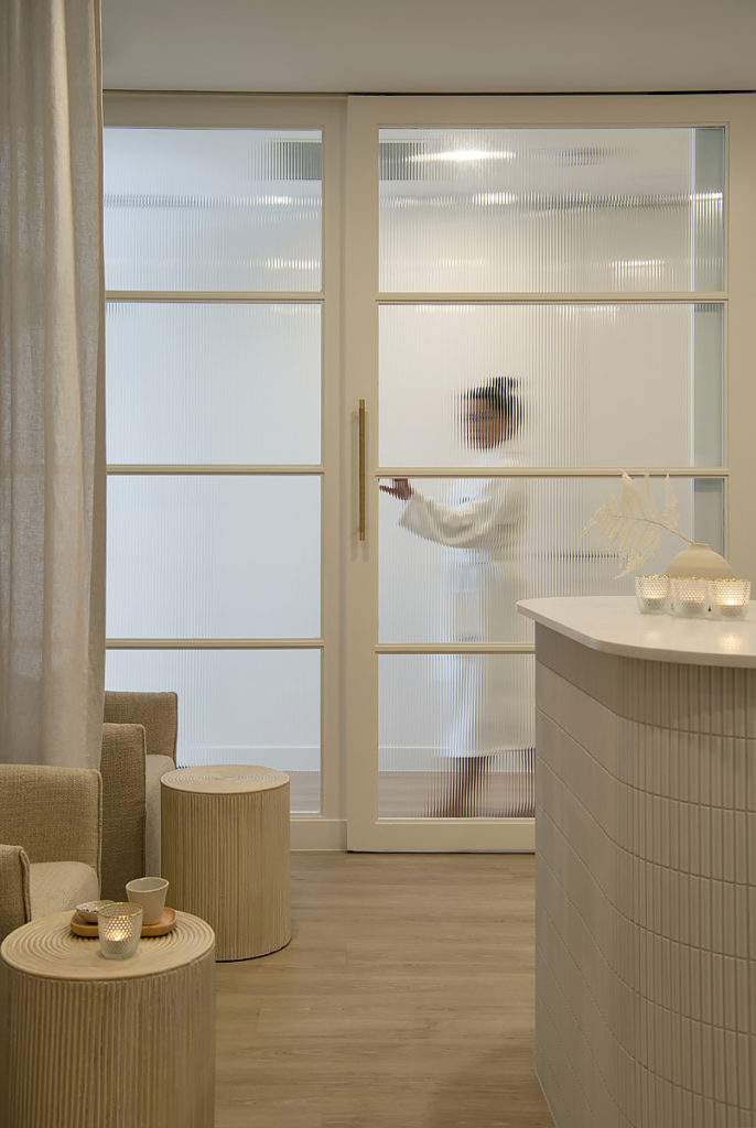 A woman walks behind a glass door in BODHI cottesloe spa