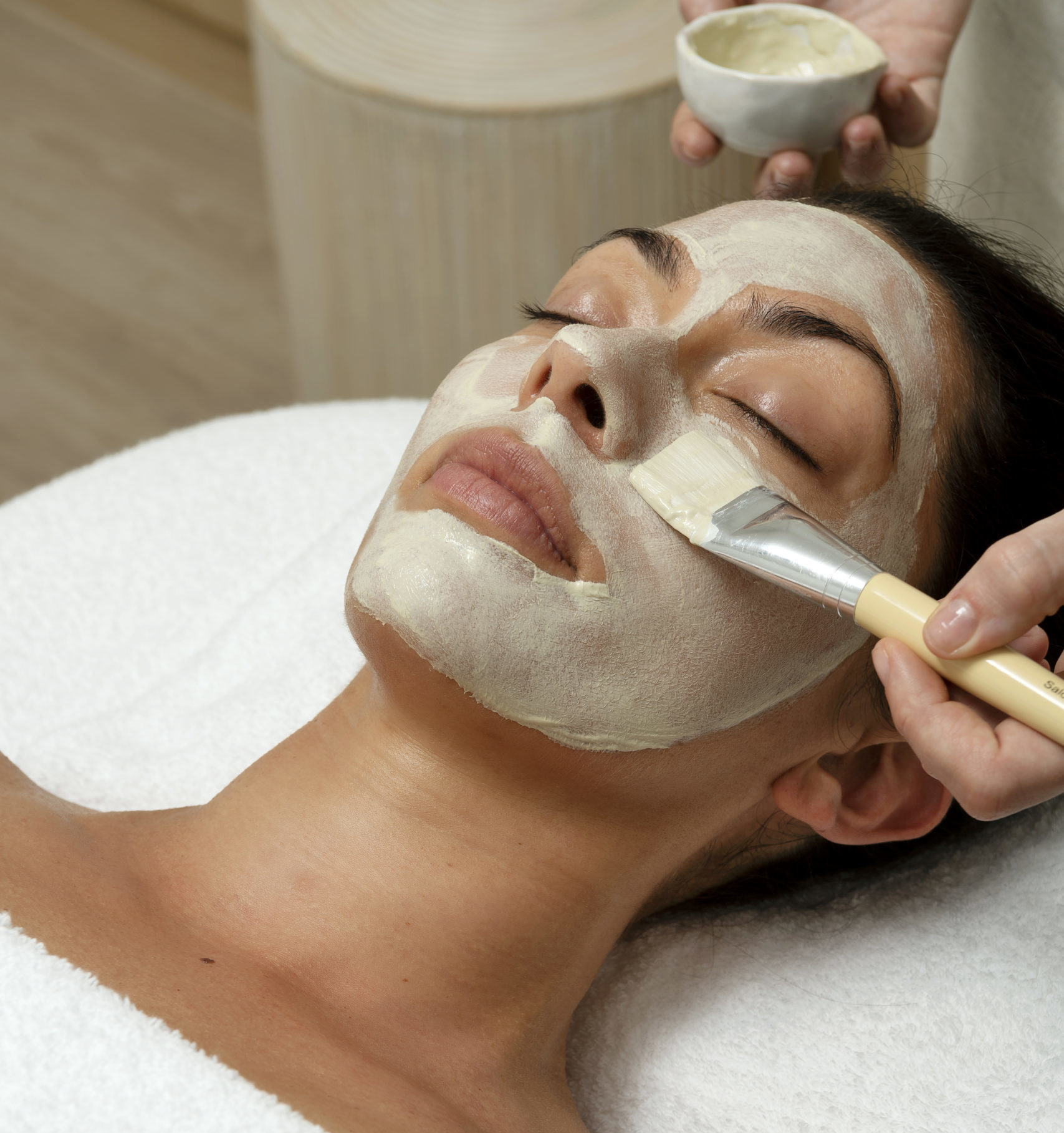 A paint brush applies a treatment to a woman's face